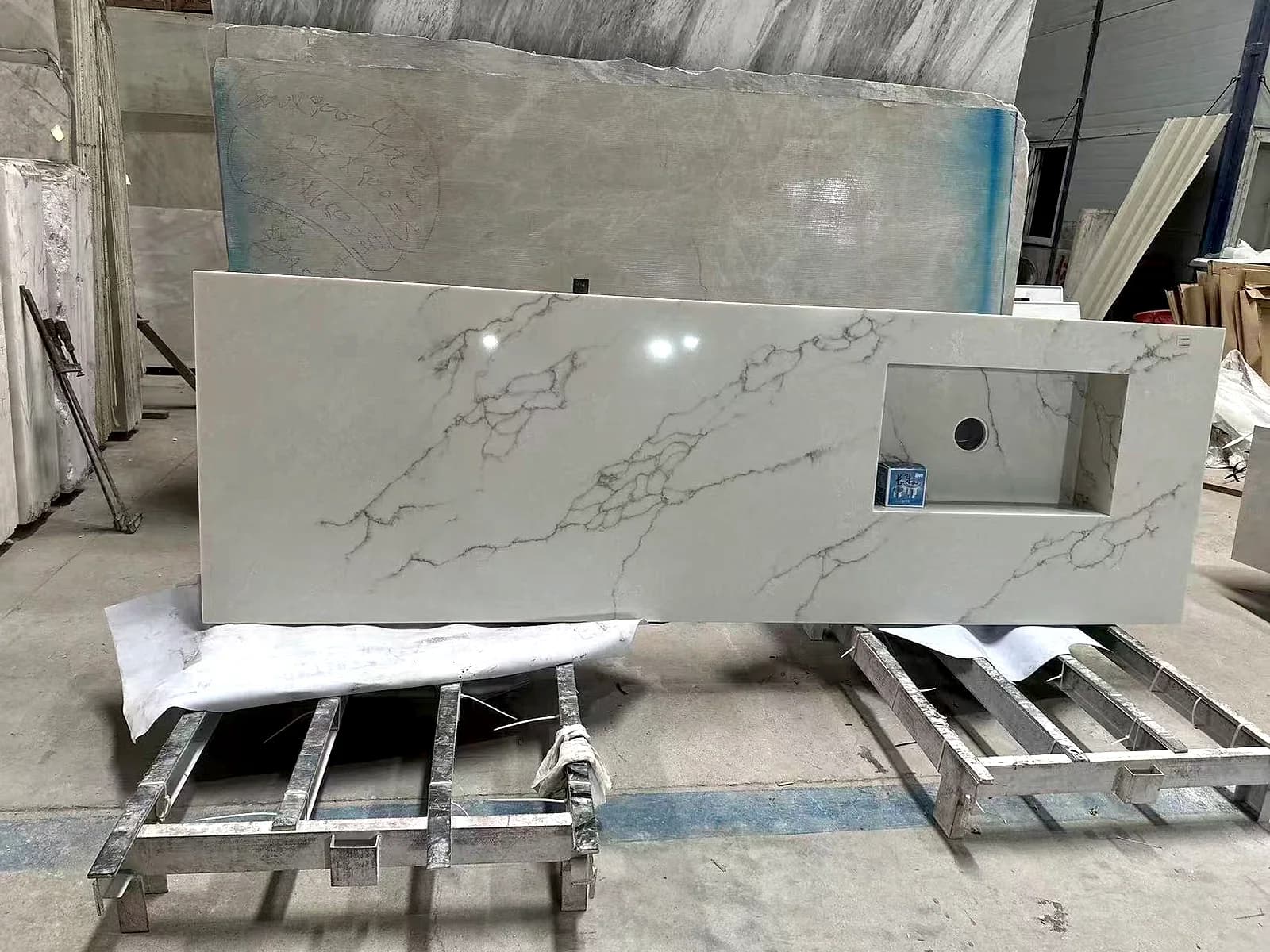 Veined light stone top with a rectangular opening and a round hole, resting on a workshop rack.