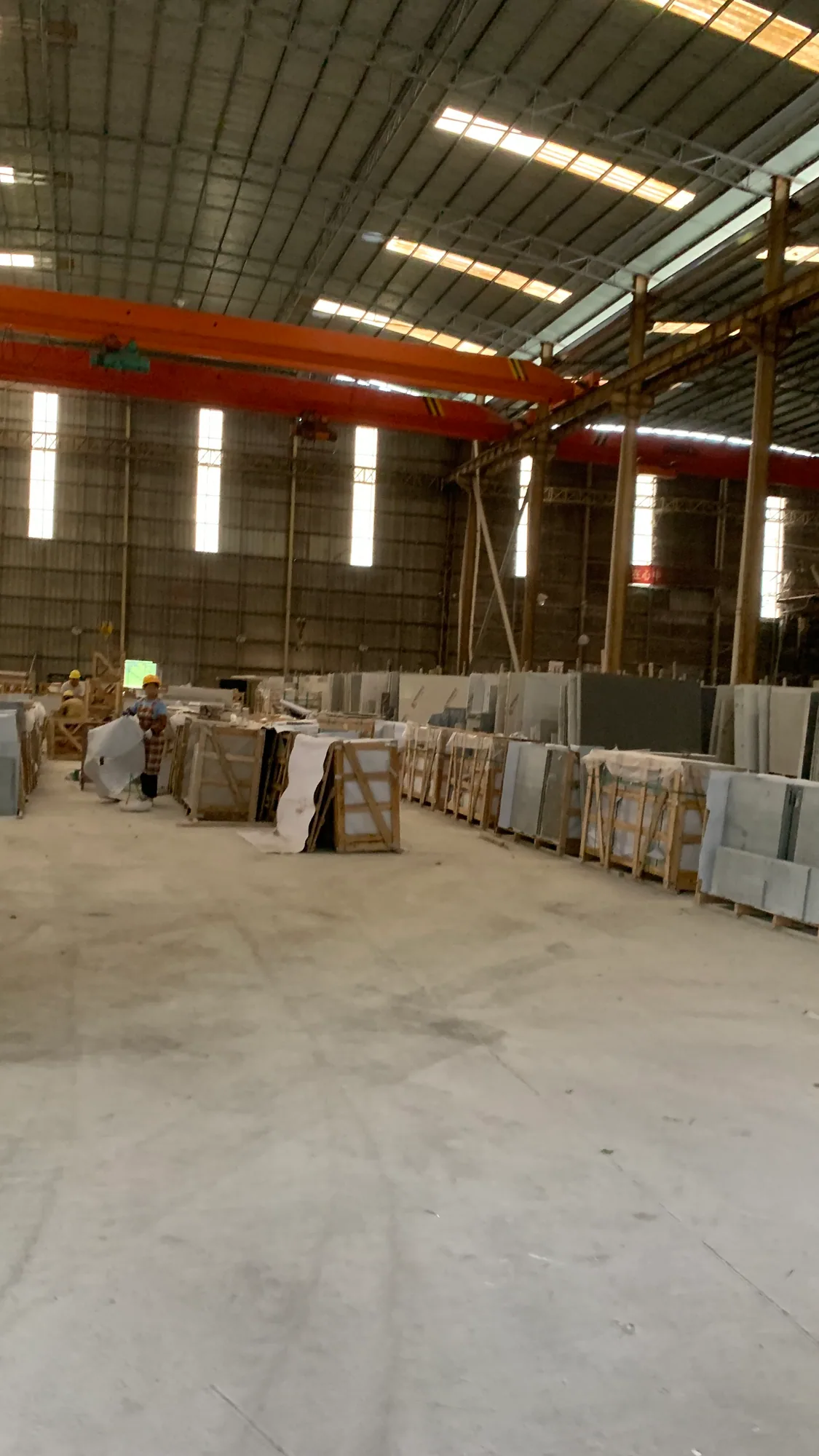 Worker preparing protective wrapping around stone components on wooden racks in a workshop.
