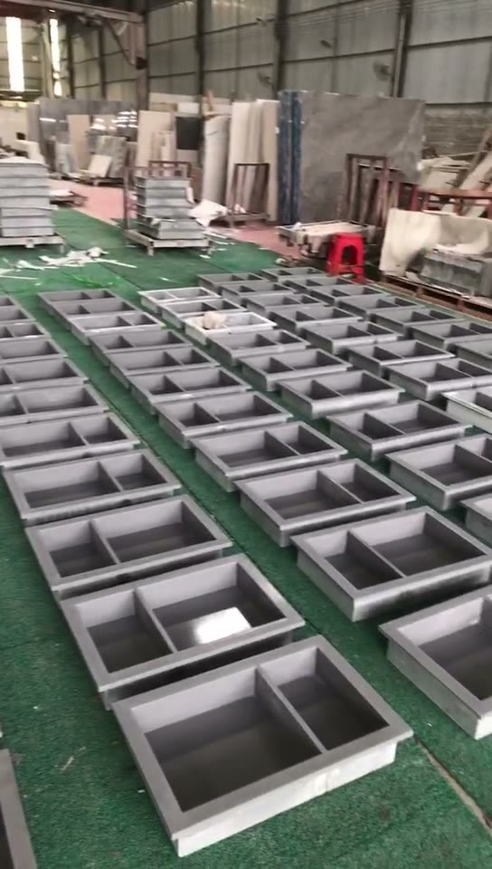 Rows of rectangular double-basin stone units are shown in the workshop.