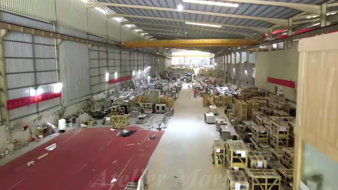 Workshop-wide views, workers handling stone, an operating work station, and wooden packing frames.